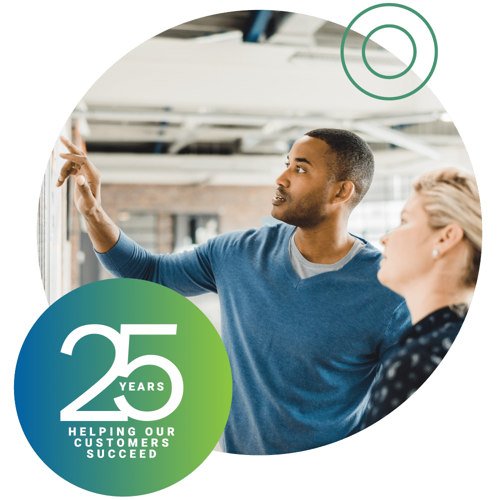 25 years of helping our customers succeed badge ontop of circle image of man and woman reviewing information on a whiteboard