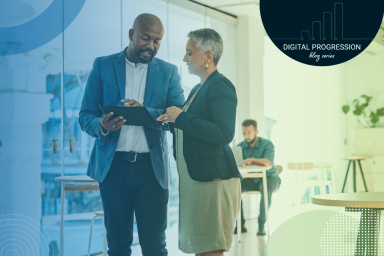 Two business professionals collaborating in a modern office, viewing a tablet with a focus on the Digital Progression.