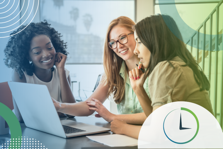 Three women in a collaborative meeting looking at a laptop screen, smiling and discussing ideas.